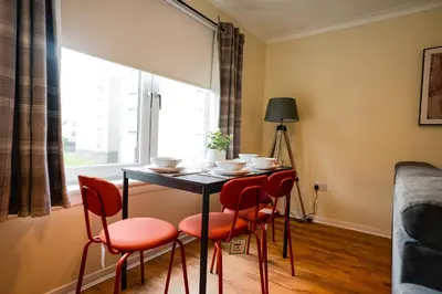 a dining room table with four chairs and a window at 2 BDR Apt At Caledonia Luxe Stays Short Lets & Serviced Accommodation Airdrie in Airdrie
