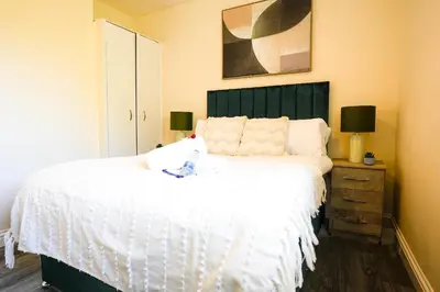 a bedroom with a white bed with a green headboard at 3 BDR House By Caledonia Luxe Stays Short Lets & Serviced Accommodation Wishaw in Wishaw