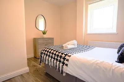 a bedroom with a bed and a mirror at 3 BDR House By Caledonia Luxe Stays Short Lets & Serviced Accommodation Wishaw in Wishaw