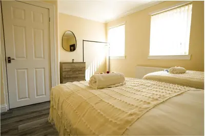 a bedroom with two beds with towels on top of it at 3 BDR House By Caledonia Luxe Stays Short Lets & Serviced Accommodation Wishaw in Wishaw