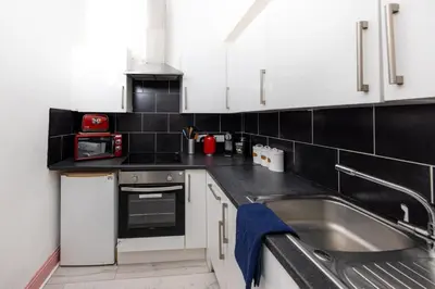 a kitchen with white cabinets and a stainless steel sink at Cosy Central Apartment by the Meadows 11 in Edinburgh