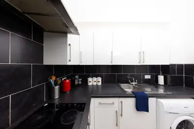a kitchen with white cabinets and a black counter top at Cosy Central Apartment by the Meadows 11 in Edinburgh