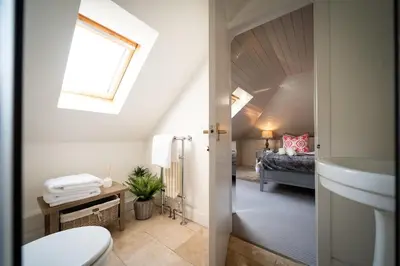 a bathroom with a toilet and a sink and a bed at Buzzard Cottage nestled in a hillside farm in Stirling