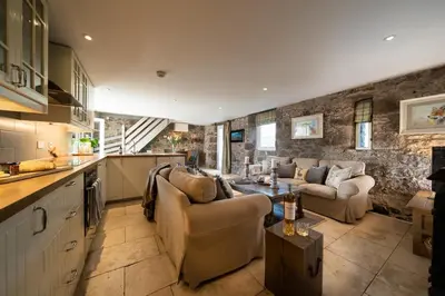 a kitchen and living room with couches and a table at Buzzard Cottage nestled in a hillside farm in Stirling
