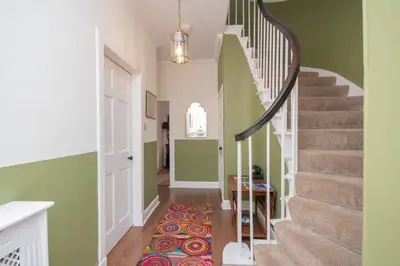 a hallway with stairs with green walls and a rug at Banrigh House in Stirling