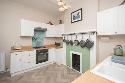 a kitchen with white cabinets and a fireplace at Banrigh House in Stirling