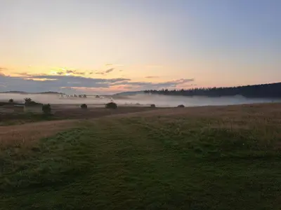 a field with fog in a field with a sunset at Three lochs holiday park Loch view 123 in Balminnoch