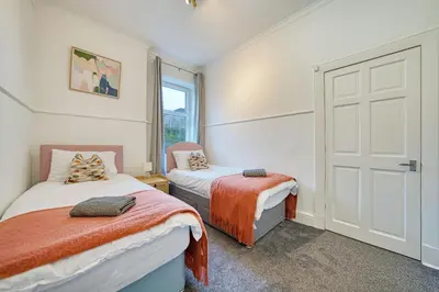 a bedroom with two beds and a door at 3BR Flat Near Maryhill Park and West End with Parking in Partick