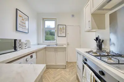 a kitchen with white cabinets and a sink at 3BR Flat Near Maryhill Park and West End with Parking in Partick