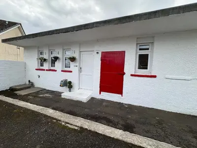a white building with a red door and windows at Muirside Cottage in Stirling