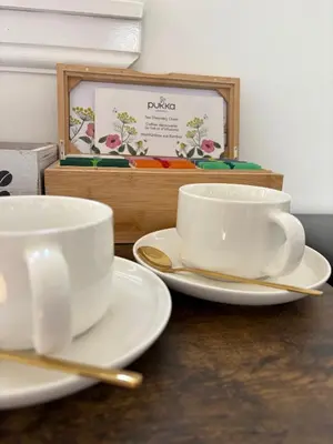 two white cups and saucers sitting on a table at Muirside Cottage in Stirling