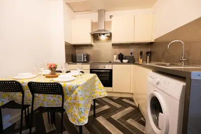 a kitchen with a table with chairs and a sink at Sauchihall Apartment in Glasgow
