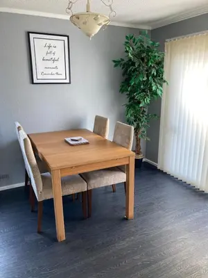 a wooden dining room table with chairs and a plant at Blackpool chalet - free parking in Moffat