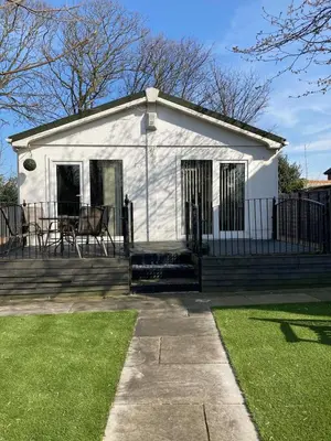 a white house with a fence and a grass yard at Blackpool chalet - free parking in Moffat