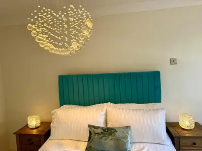 a bed with a green headboard and two night stands at Modern 4-Bed Family Home in Solihull in Moffat