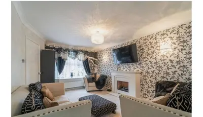 a living room with a couch and a fireplace at Modern 4-Bed Family Home in Solihull in Moffat