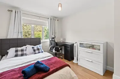 a bedroom with a bed with a desk and a keyboard at Polmont Haven: Spacious 4- Bedroom Retreat in Polmont