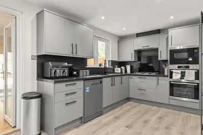 a kitchen with white cabinets and stainless steel appliances at Polmont Haven: Spacious 4- Bedroom Retreat in Polmont