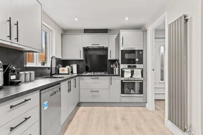 a kitchen with white cabinets and white appliances at Polmont Haven: Spacious 4- Bedroom Retreat in Polmont