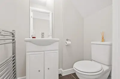 a white bathroom with a toilet and a sink at Polmont Haven: Spacious 4- Bedroom Retreat in Polmont