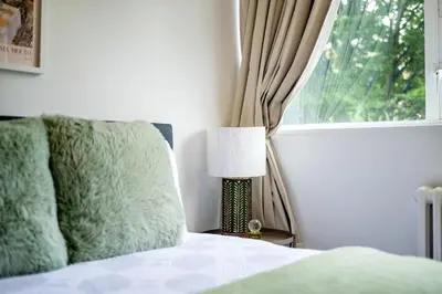 a bedroom with a bed with a lamp and a window at Cozy 2 bedroom London Flat in Heart of Pimlico in Moffat