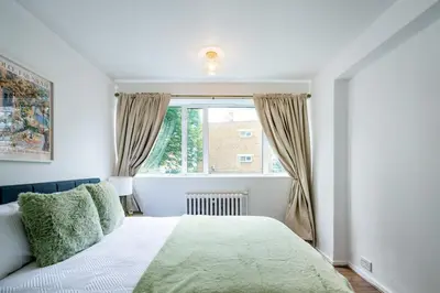 a white bedroom with a bed and a window at Cozy 2 bedroom London Flat in Heart of Pimlico in Moffat