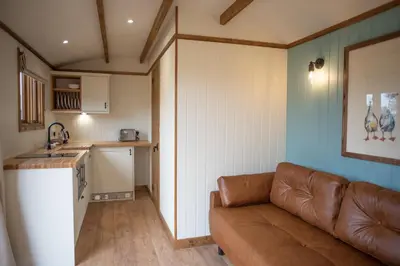 a living room with a couch and a kitchen at Pentland Shepherd Huts in Penicuik