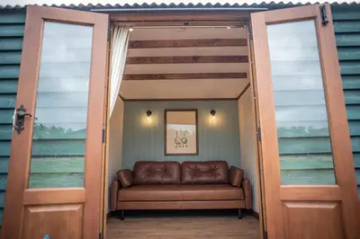 a door leading into a living room with a couch at Pentland Shepherd Huts in Penicuik