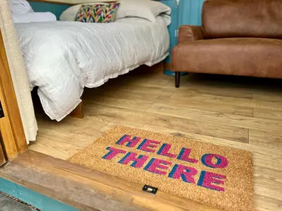 a hello there rug on a floor next to a bed at Pentland Shepherd Huts in Penicuik