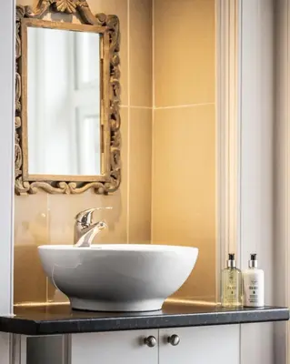 a bathroom with a sink and a mirror on a counter at Cairns Farmhouse in Kirknewton