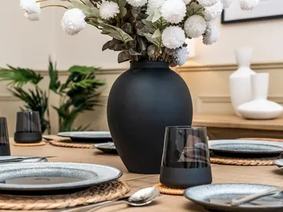 a wooden table with a black vase with white flowers at Pass the Keys Beautiful Modern Historical Flat Close to Castle in Edinburgh