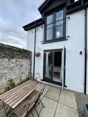 a wooden bench in front of a white house at Kilmory Sea View in Lochgilphead
