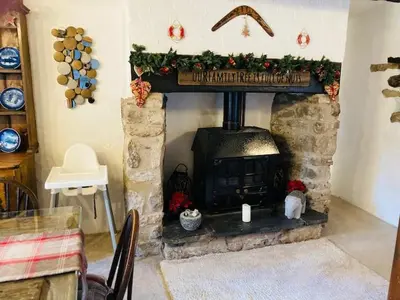 a living room with a fireplace with christmas decorations at Oronsay, 2 Weint End Cottages, Great Urswick, Ulverston Cumbria LA120SP in Moffat