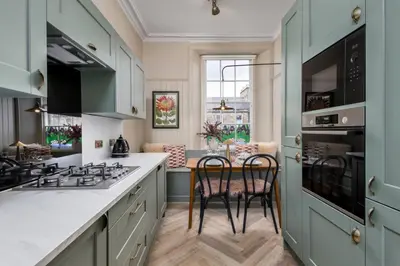 a kitchen with green cabinets and a counter with two chairs at The Allan Maisonette Charming Georgian Retreat in Stirling