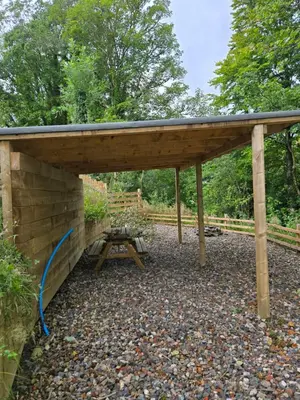 a wooden pavilion with a picnic table under it at The Tearoom Tarbet in Tarbet