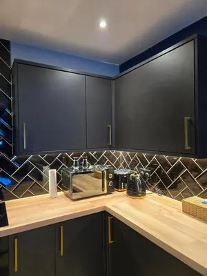a kitchen with black cabinets and a toaster on a counter at The Tearoom Tarbet in Tarbet