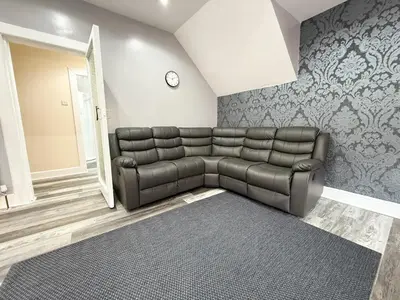 a living room with a leather couch and a mirror at Glasgow Home Newly Refurbished in Glasgow