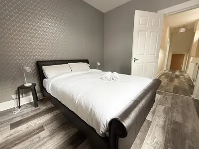 a bedroom with a large bed with white sheets at Glasgow Home Newly Refurbished in Glasgow