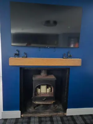 a blue wall with a fireplace with a tv above it at The Post Office Tarbet in Tarbet
