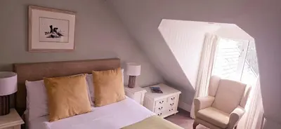 a bedroom with a bed and a chair and a window at Glenisle Hotel in Isle of Arran