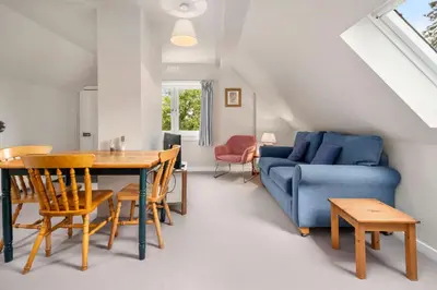 a living room with a table and a blue couch at Rural 1-Bed Retreat at Stunning Raera Farm in Kilninver