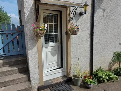 a white door with two baskets of flowers on it at 3 bed, 500mtrs to castle and stunning views in Stirling