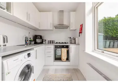 a white kitchen with a washer and dryer in it at Elegant Flat in a Serene Edinburgh Neighbourhood in Edinburgh