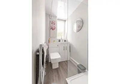 a white bathroom with a toilet and a window at Elegant Flat in a Serene Edinburgh Neighbourhood in Edinburgh