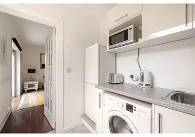 a white kitchen with a washing machine and a sink at Elegant Flat in a Serene Edinburgh Neighbourhood in Edinburgh