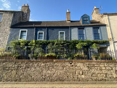 a house behind a stone wall with a fence at Shipmaster's Townhouse in Queensferry