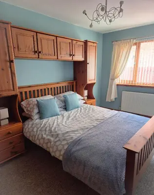 a bedroom with a bed with blue walls and a window at The Yard Bungalow in Sanquhar
