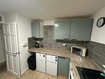 a small kitchen with green cabinets and a microwave at 3 bedroom apartment in Cumbernauld