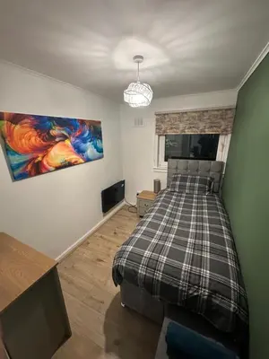 a bedroom with a bed and a painting on the wall at 3 bedroom apartment in Cumbernauld