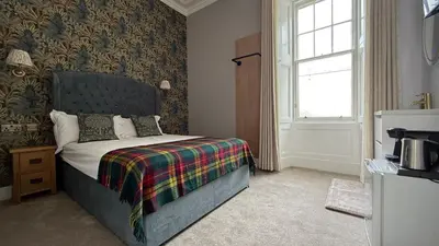 a bedroom with a bed with a blanket and a window at Armadillo Guest House- Adults Only in Edinburgh
